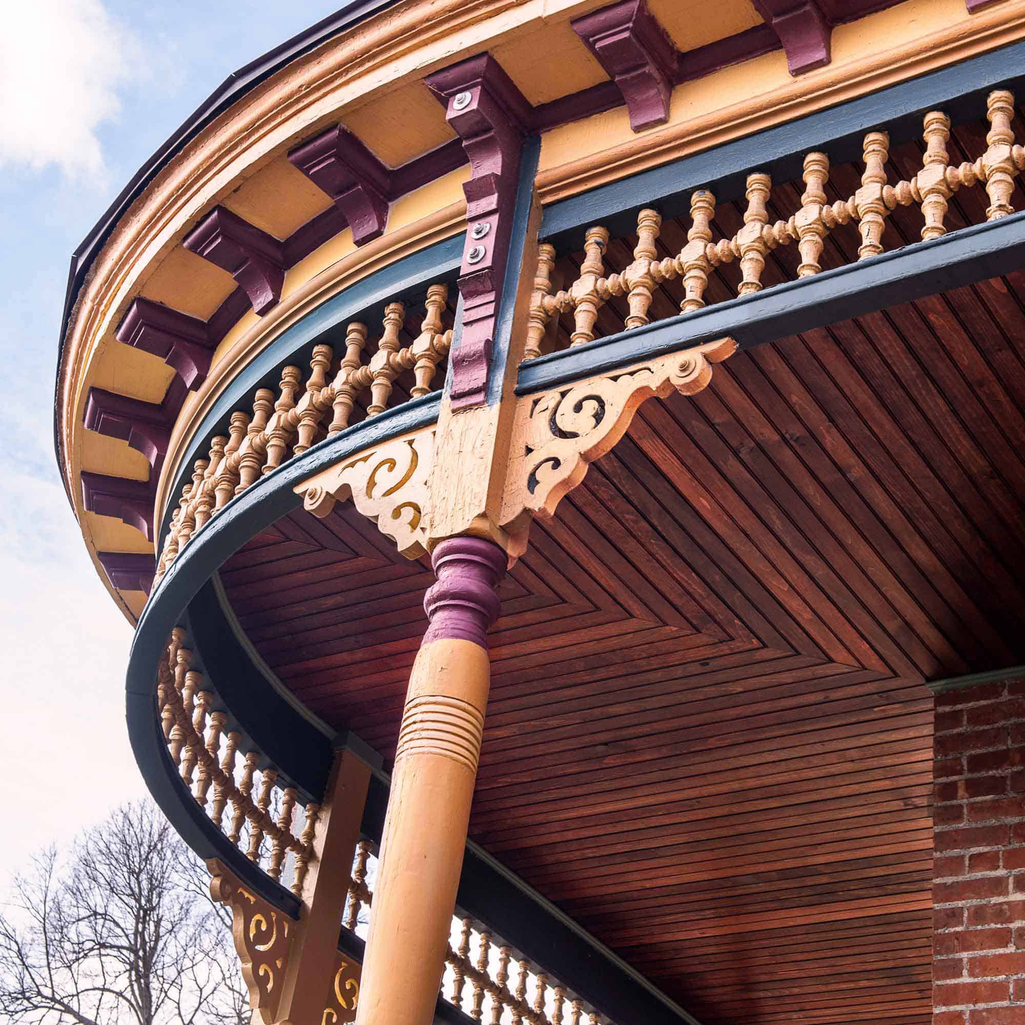 A look up toward the ornate brackets and wooden gingerbread details on a Victorian Porch.